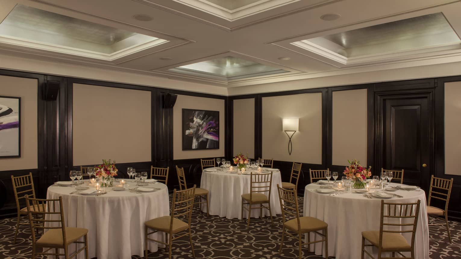 Small round banquet tables and chairs under recessed ceiling