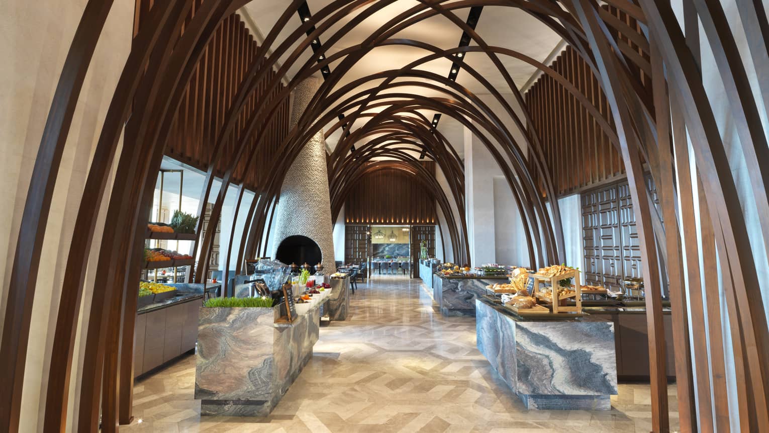 Soaring ceilings, wood arches over marble buffets in modern Arabian Design hallway