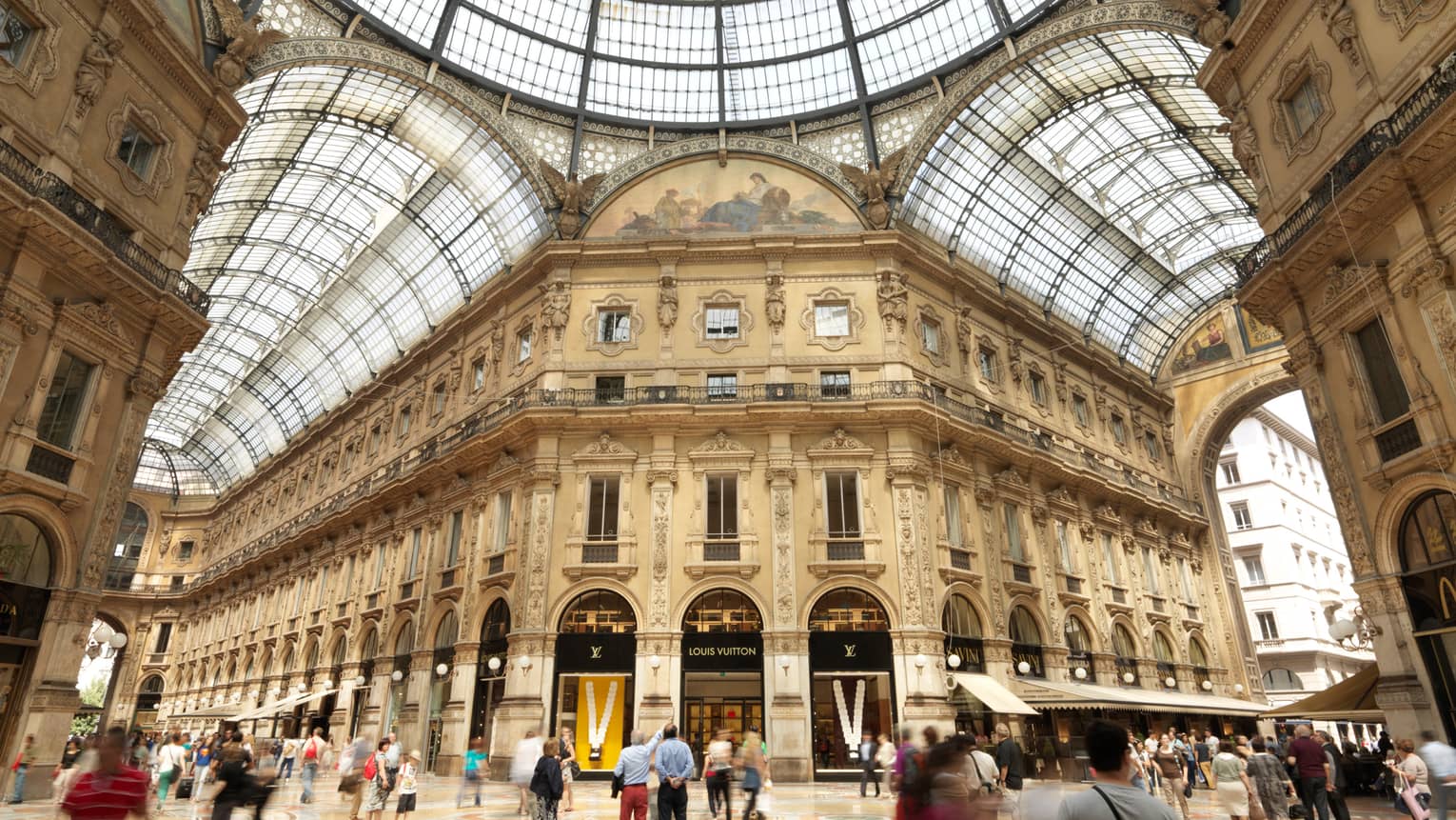 Shoppers gathered in  historic Galleria Vittorio Emanuele building with soaring ceilings, shops