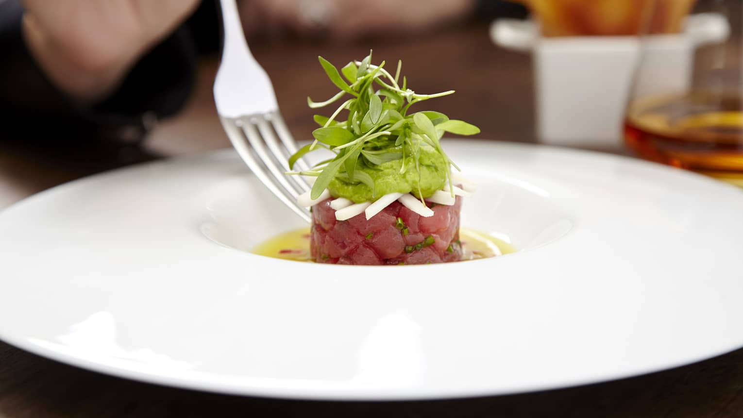  Fork over plate with small tartare topped with greens