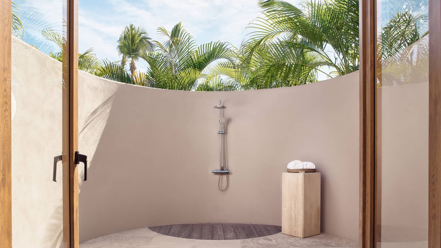 Arena Beach House high-walled stucco outdoor shower, palm trees providing privacy and shade