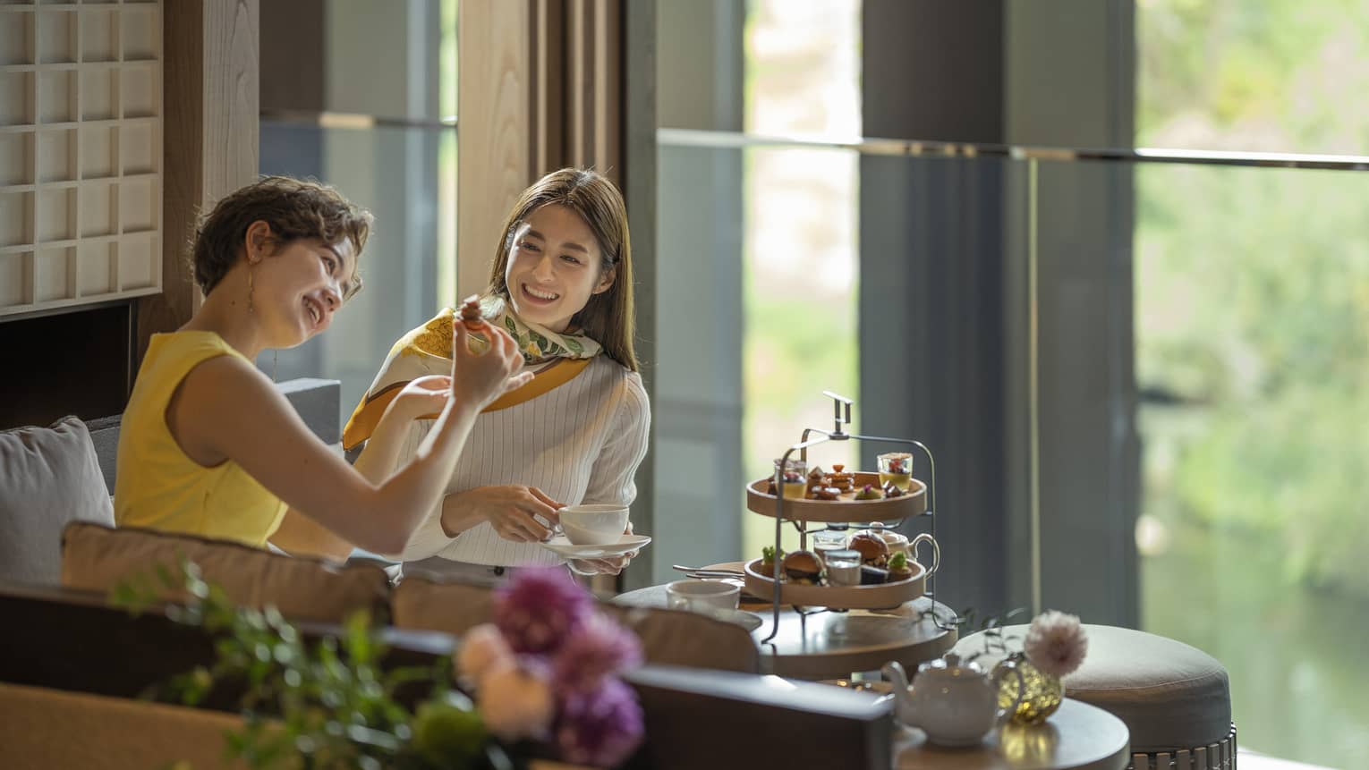 Two laughing women enjoy afternoon tea at The Lounge 