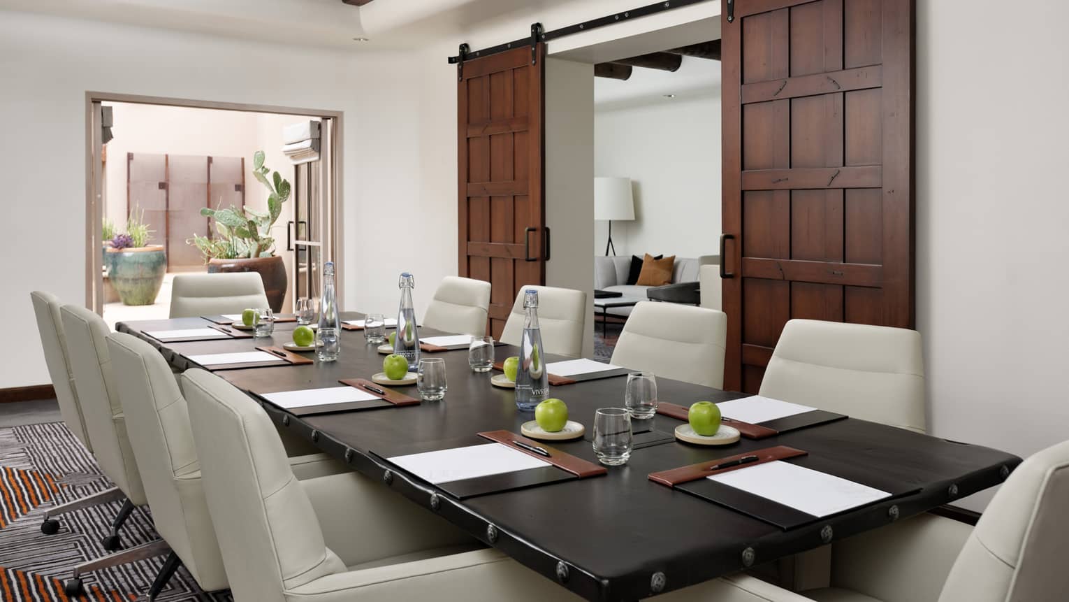 A meeting rom with leather chairs around a large rectangular table, two large wooden sliding door are on a wall.