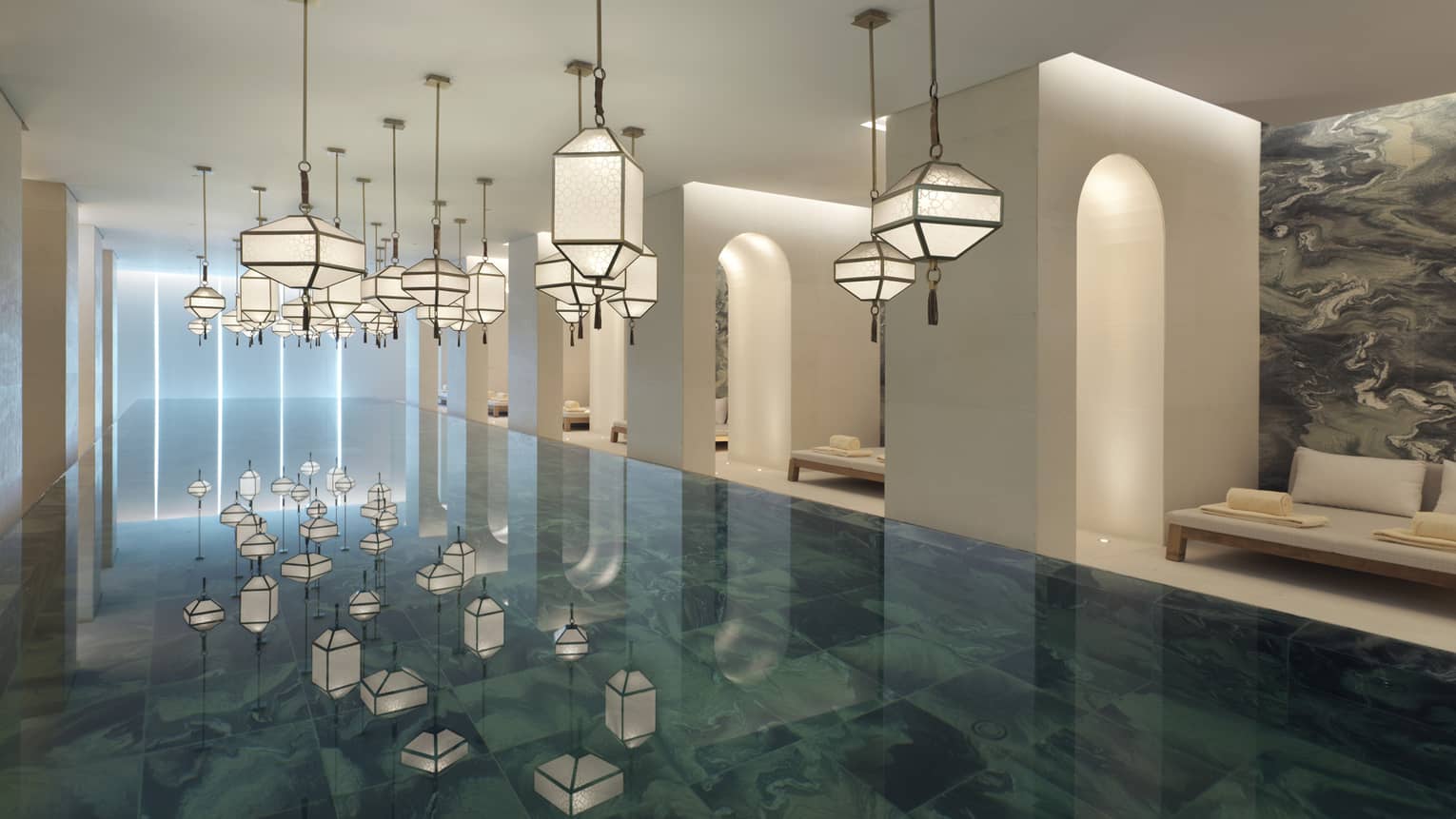 Several modern white lanterns hanging above Indoor Spa Pool, reflected on water 