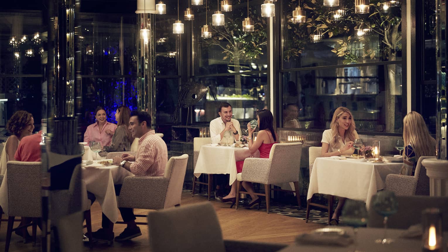 Patrons dining at AQUA under hanging low lighting in an intimate atmosphere