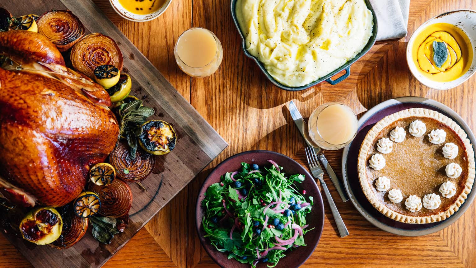 An aerial shot of a thanksgiving dinner including a roasted turkey with vegetables, mashed potatoes, salad and pumpkin pie