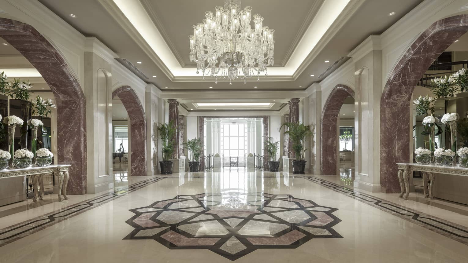 The marble lobby with a crystal chandelier above a mosaic.
