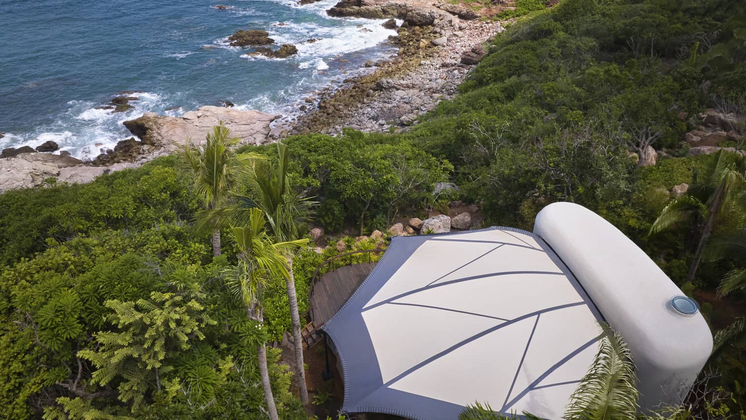 Aerial view of a private luxury tent nestled in the jungle, next to the beach