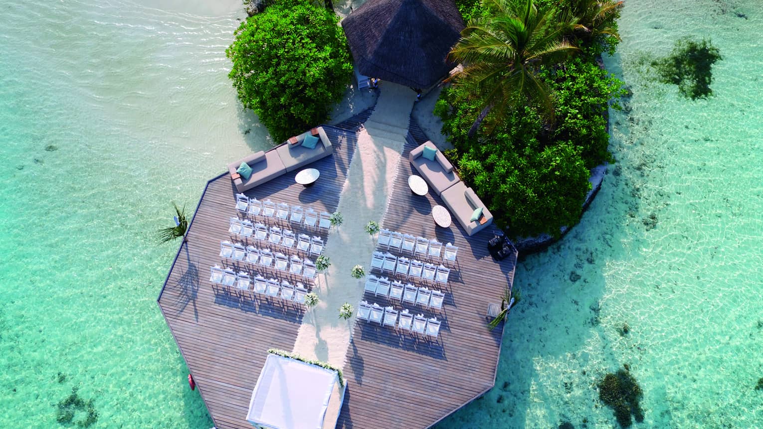Aerial view of wedding ceremony, rows of white chairs on dock over lagoon