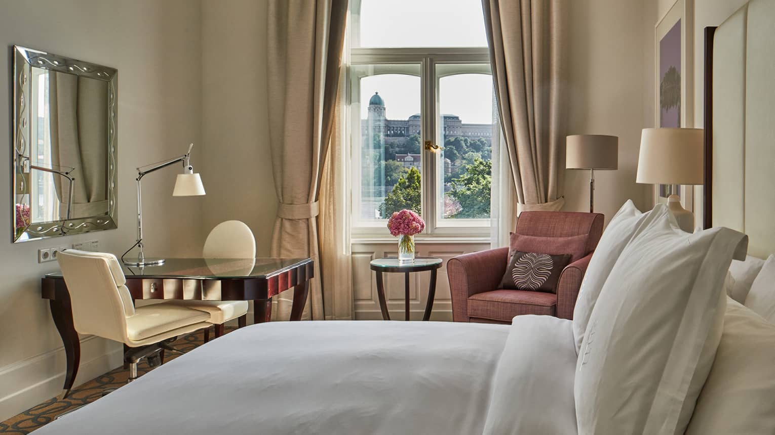 A hotel room with bed, chairs, small table and window.