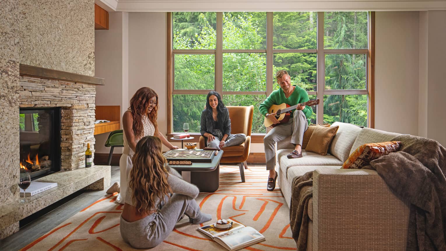 Cozy gathering in a luxury vacation rental living area at Four Seasons Whistler. Four people enjoy leisure time together; one man plays guitar while seated on a chair, and three women engage in conversation and board games. The room is warmly decorated with a stone fireplace, large windows showcasing a forest view, a plush sofa, and vibrant geometric-patterned rugs.,Cozy gathering in a luxury vacation rental living area at Four Seasons Whistler. Four people enjoy leisure time together; one man plays guitar while seated on a chair, and three women engage in conversation and board games. The room is warmly decorated with a stone fireplace, large windows showcasing a forest view, a plush sofa, and vibrant geometric-patterned rugs.