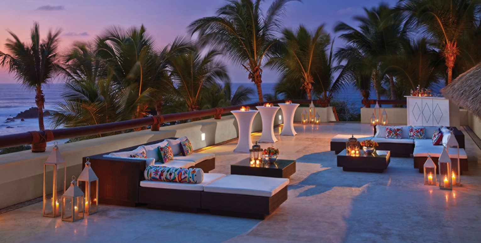 Trendy outdoor lounge at dusk, overlooking the beach