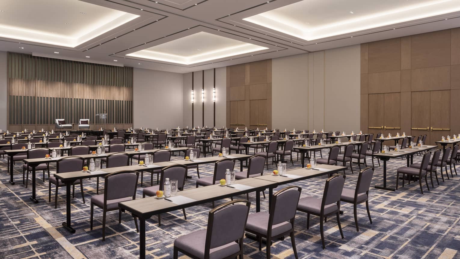 A large meeting room with longe tables and chairs facing a one side of the space.