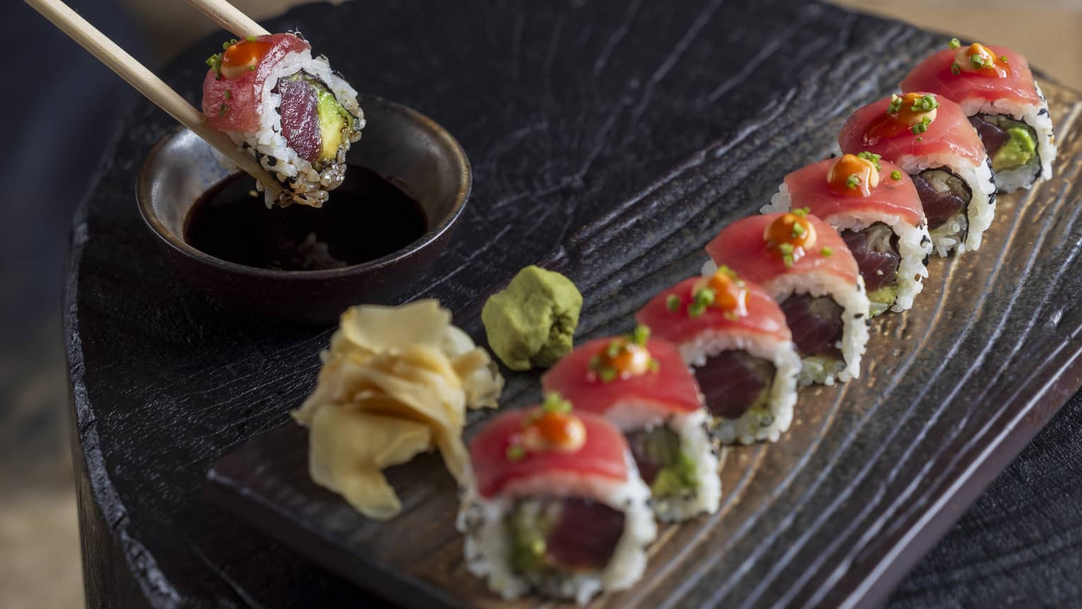 Yellowfin tuna sushi roll served on a black wood-grain platter