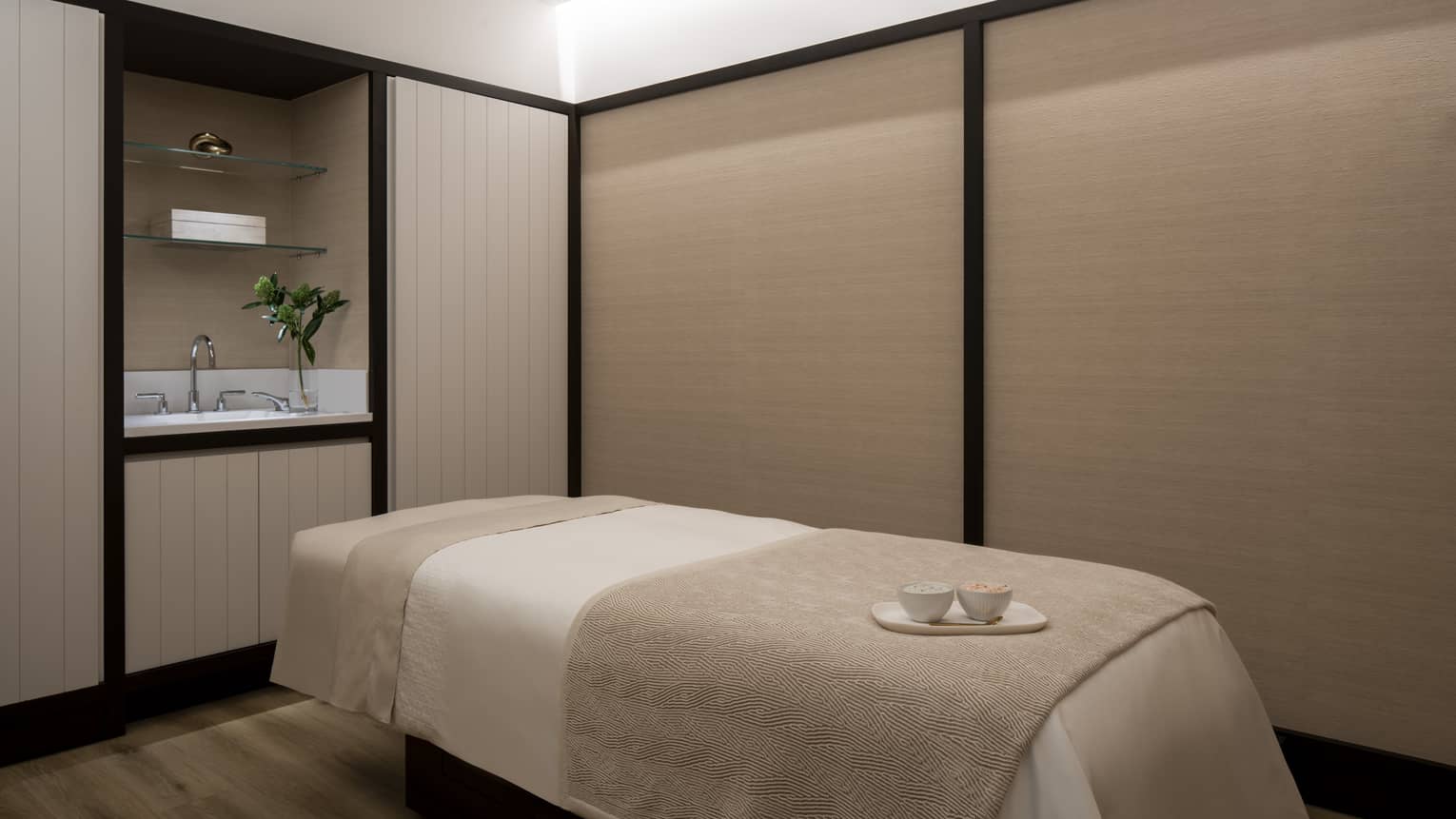 A beige massage bed with two teacups resting upon it. 