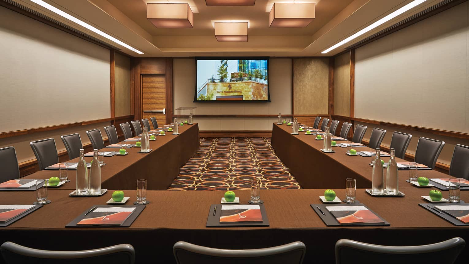 Magenta large ballroom lined with modular meeting tables, chairs facing screen