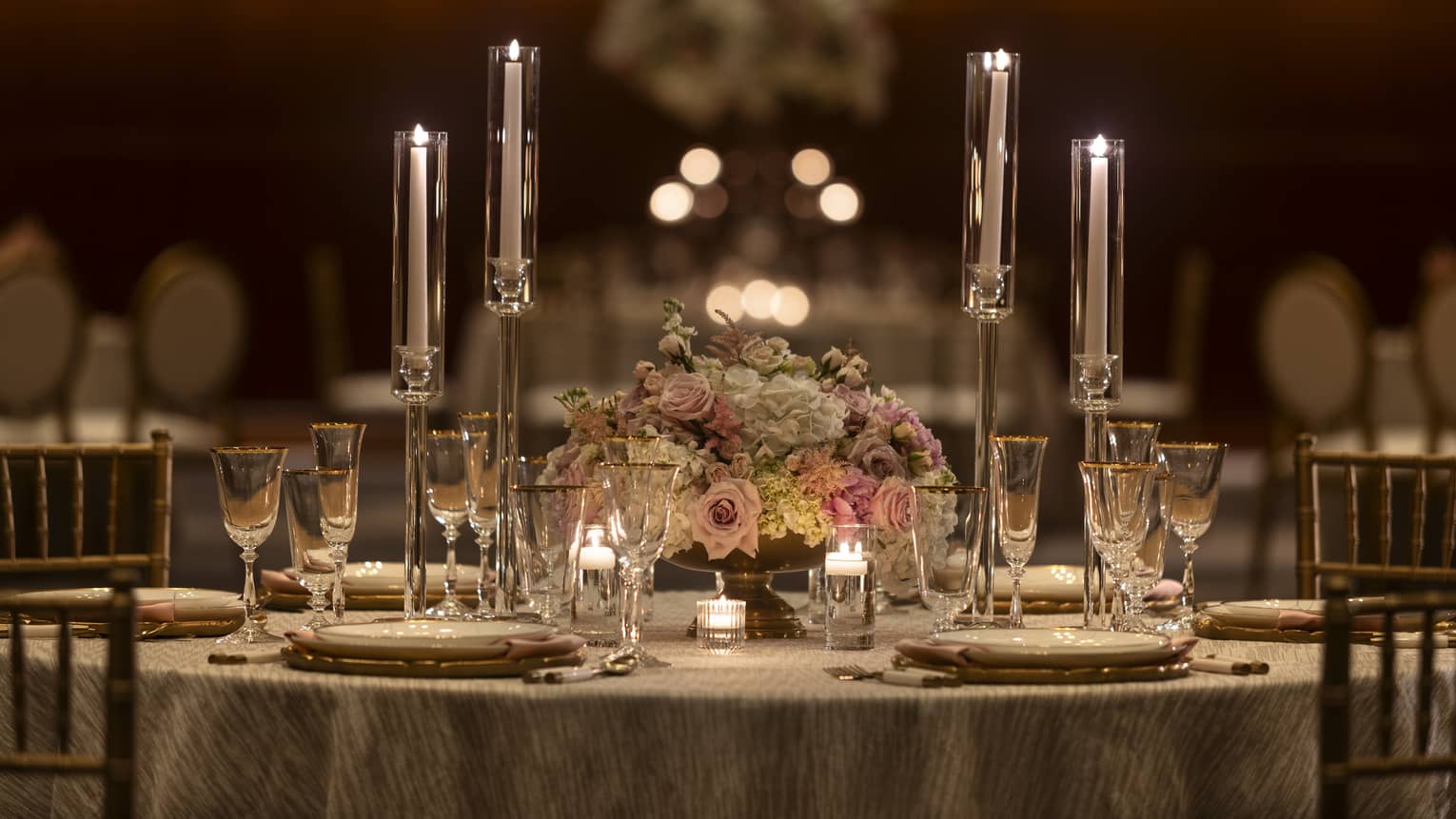 A table with candles, flowers, and table settings.