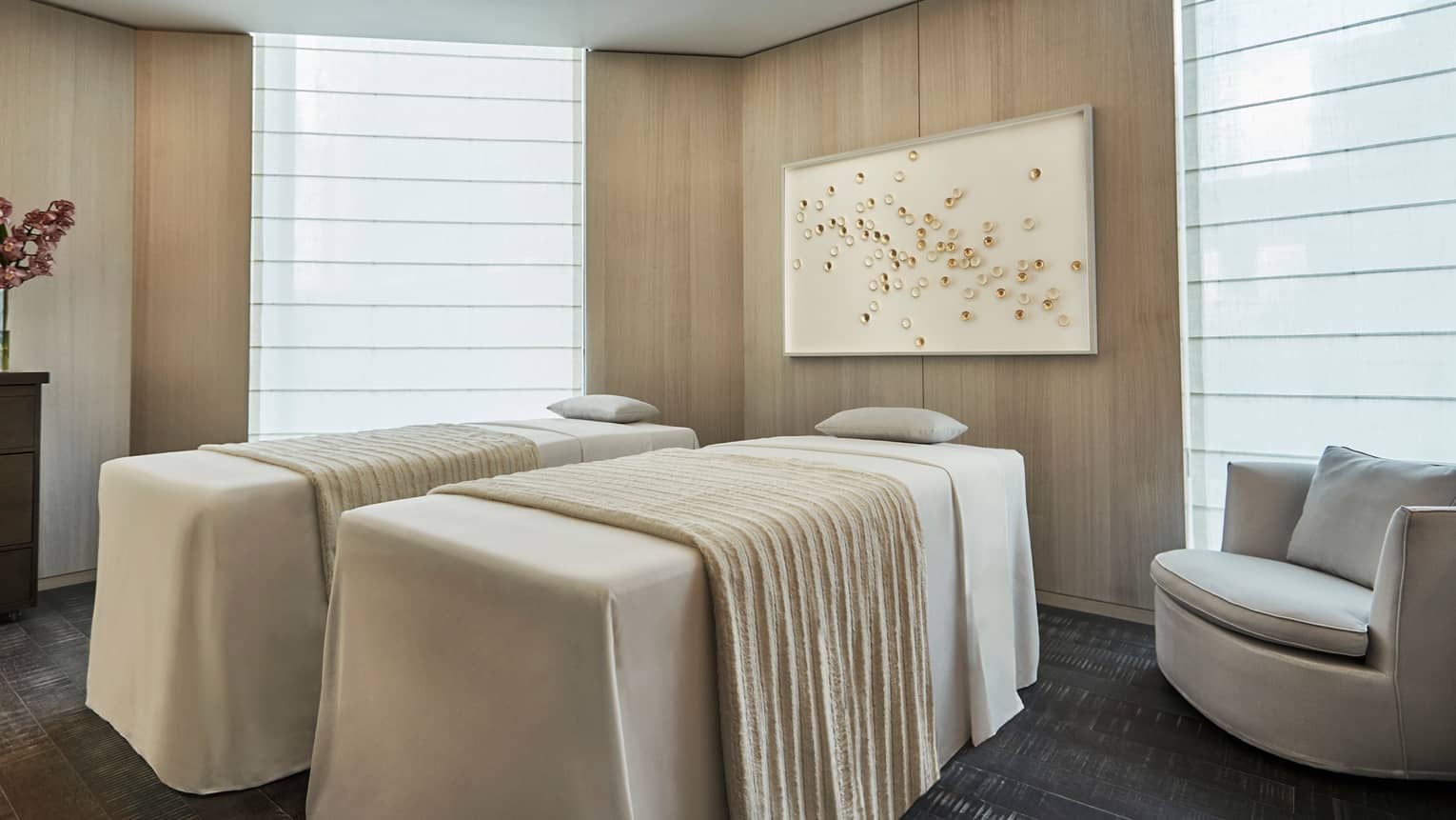 Side-by-side massage tables with white blankets in spa room