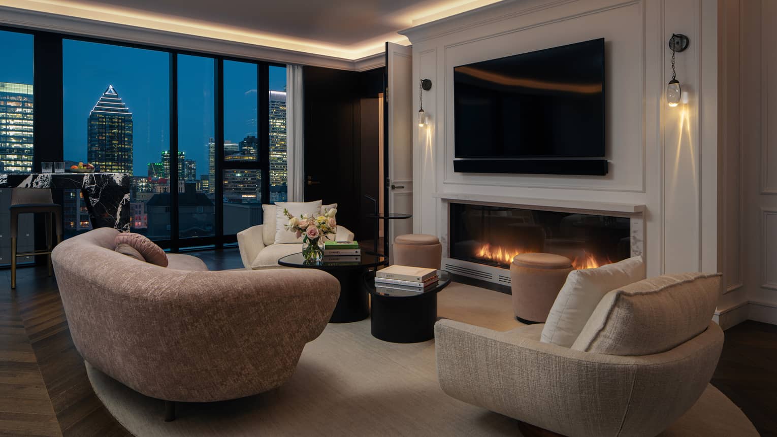 Living room with modern curved sofa and chairs, fireplace, TV and city evening view