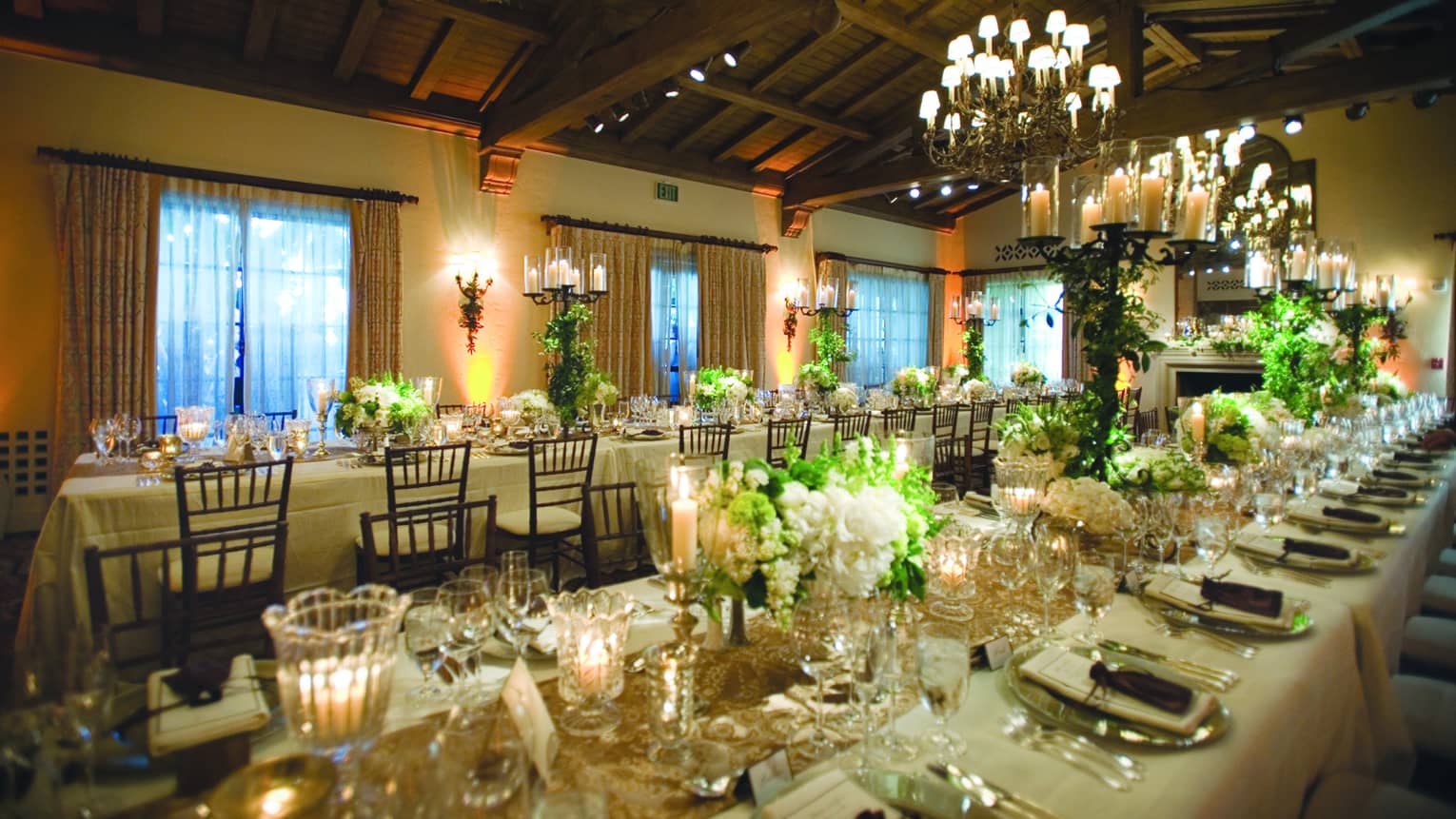 Long wedding banquet tables with glowing candles, white flowers 