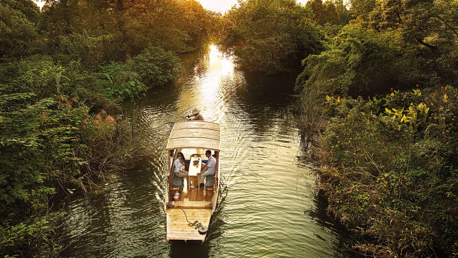 Couple in Chinese wooden row boat travelling through West Lake marsh