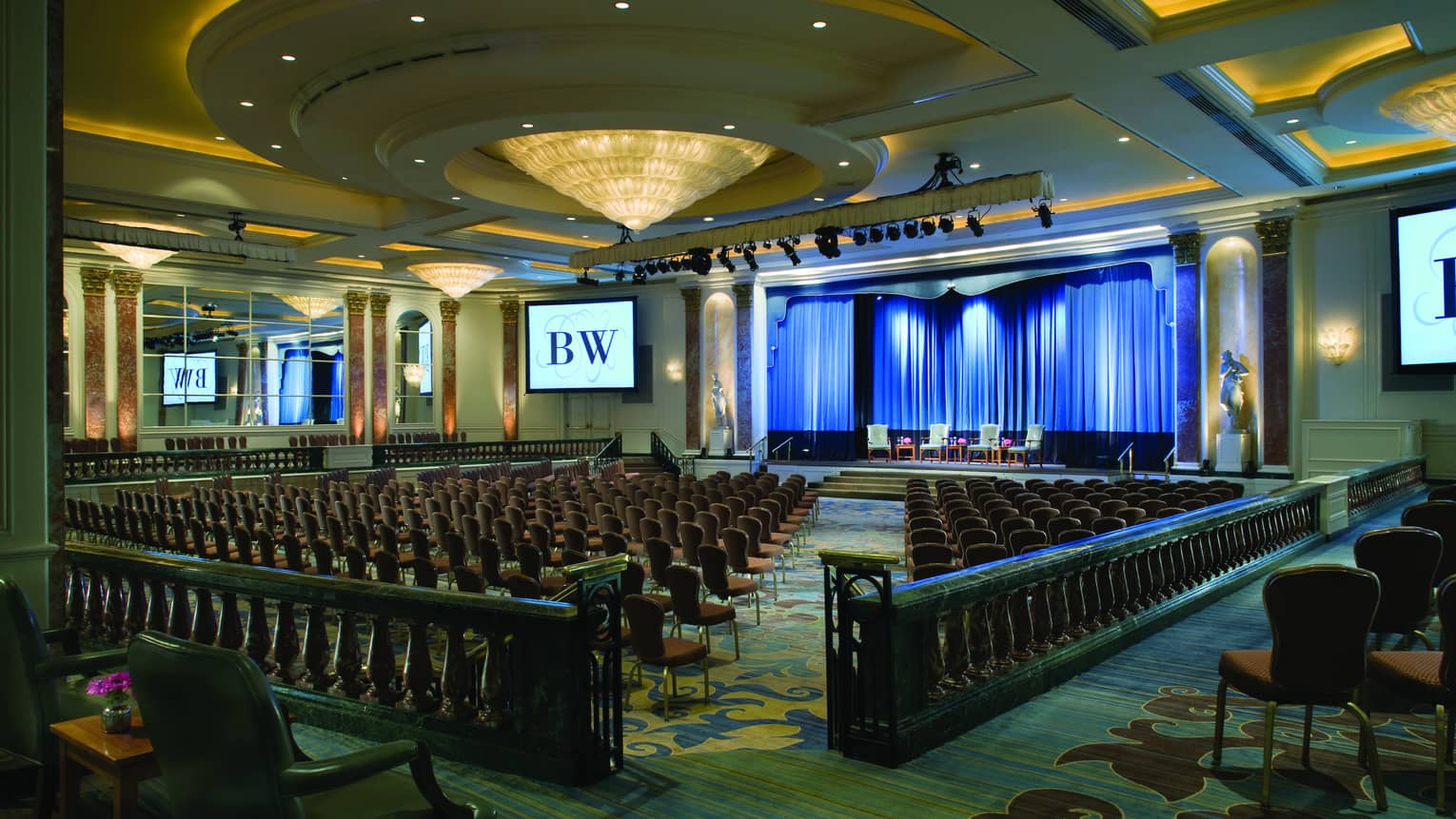 Ballroom with meeting chairs in conference set up under large dome ceiling, cone-shaped chandelier