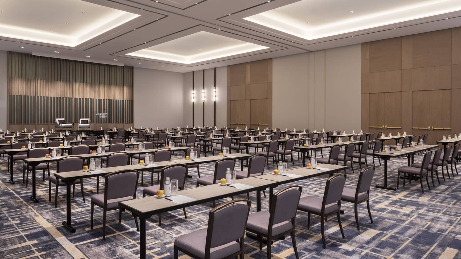 A large meeting room with longe tables and chairs facing a one side of the space.