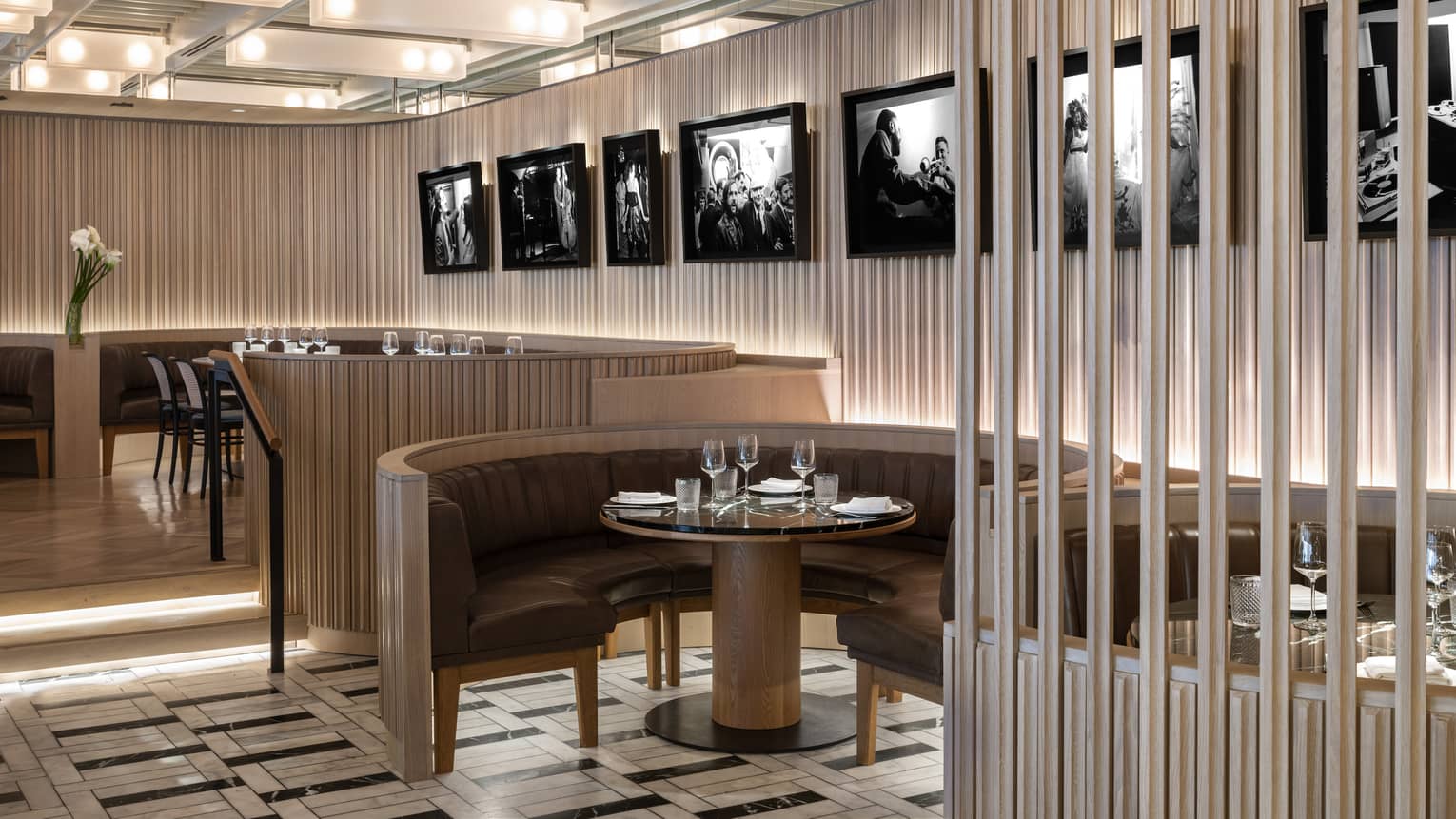 Thin, vertical panels of light-stained wood line the walls and the outside edges of the curved banquet-style tables at MARCUS Restaurant, with black-and-white photography hanging on the walls