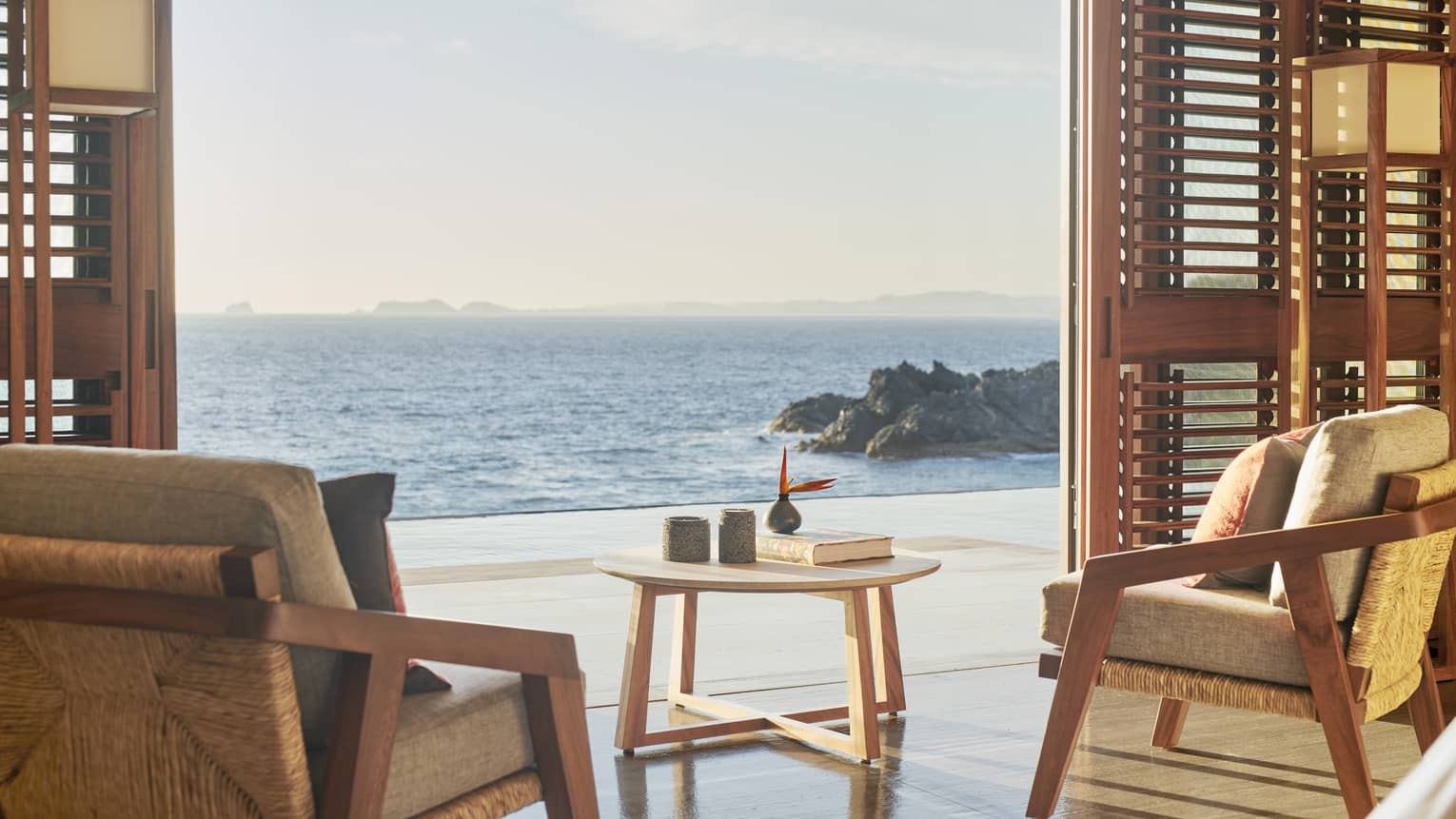 Resort bedroom sitting area, with shutter doors opening to ocean-view terrace