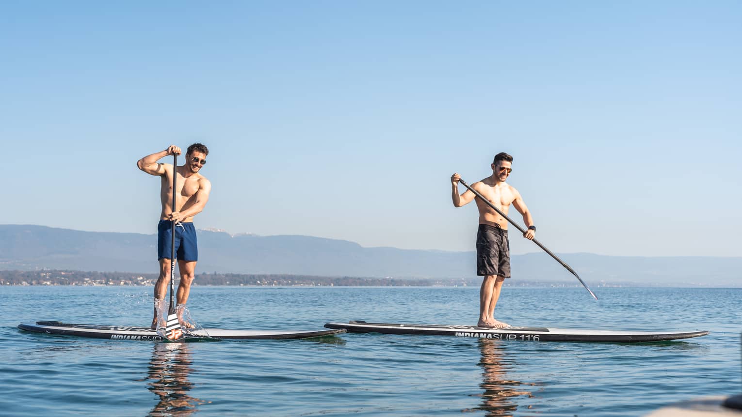 Two men stand-up paddleboarding on Lake Geneva