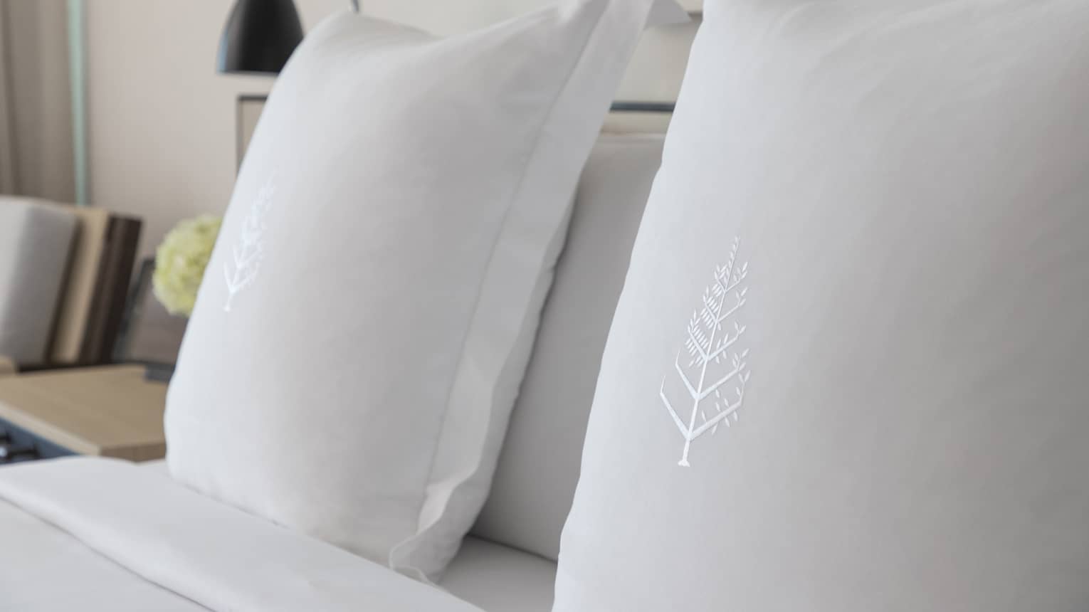 Two white sham pillows on bed with embroidered Four Seasons logos