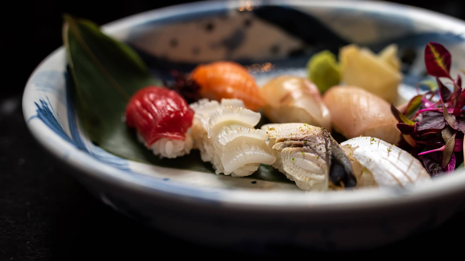 Colourful nigiri selection on palm leaf in blue-and-white bowl