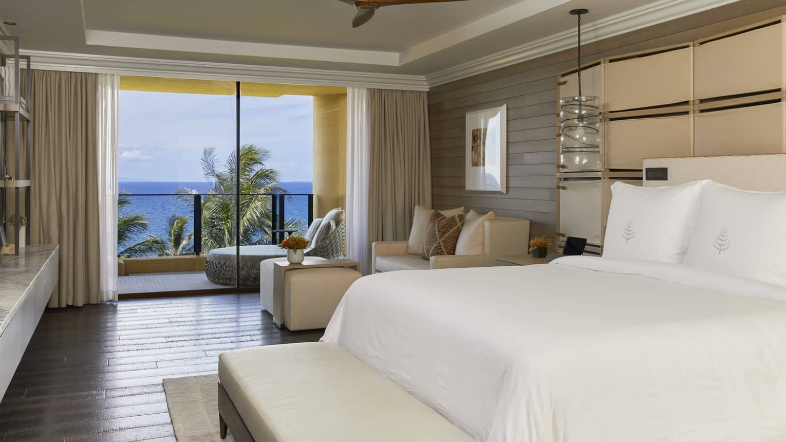 Hotel suite bedroom with sitting area and ocean view
