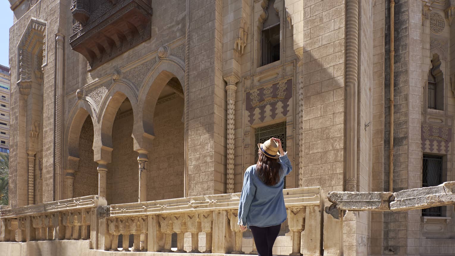 Woman looks up at historic palace exterior in Alexandria, Egypt 