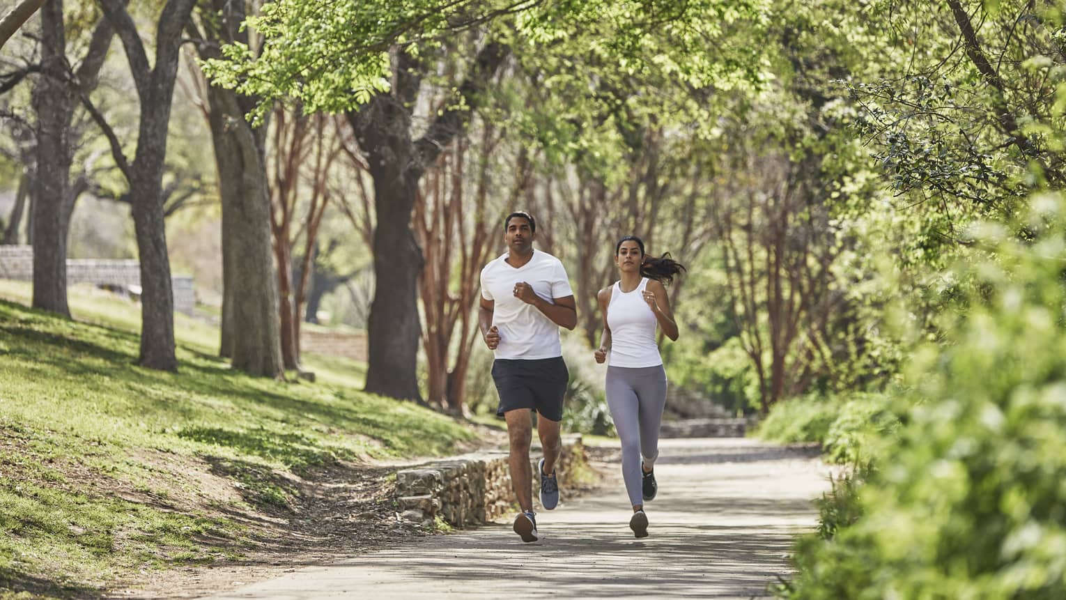 Two guests run together along a tree-lined path
