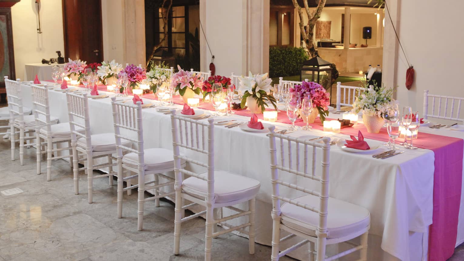 Residence Villa reception dinner, long banquet table with pink linens and flowers