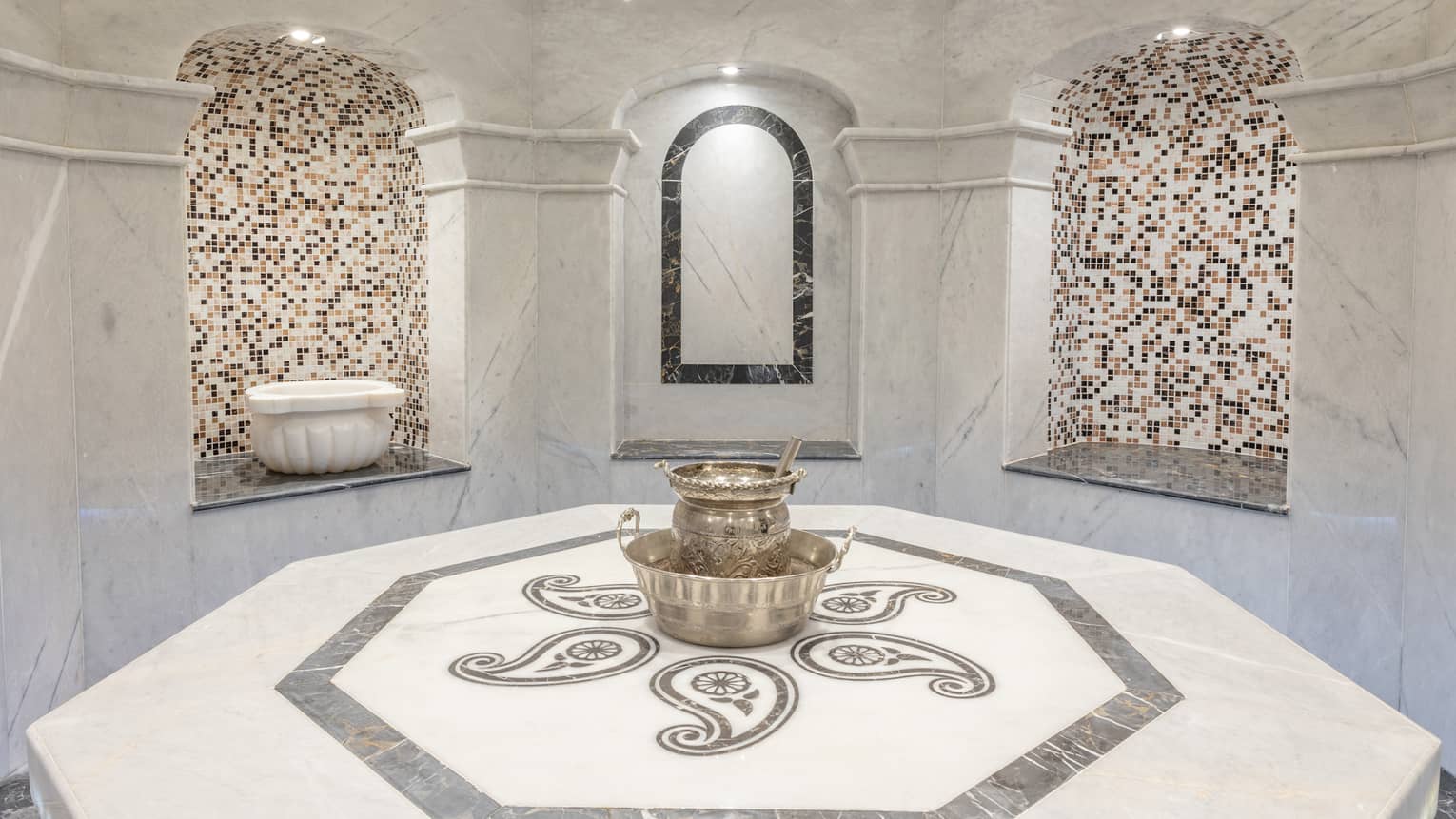 Grey and white marble hammam room with octagonal hammam in centre with brass fixture in c