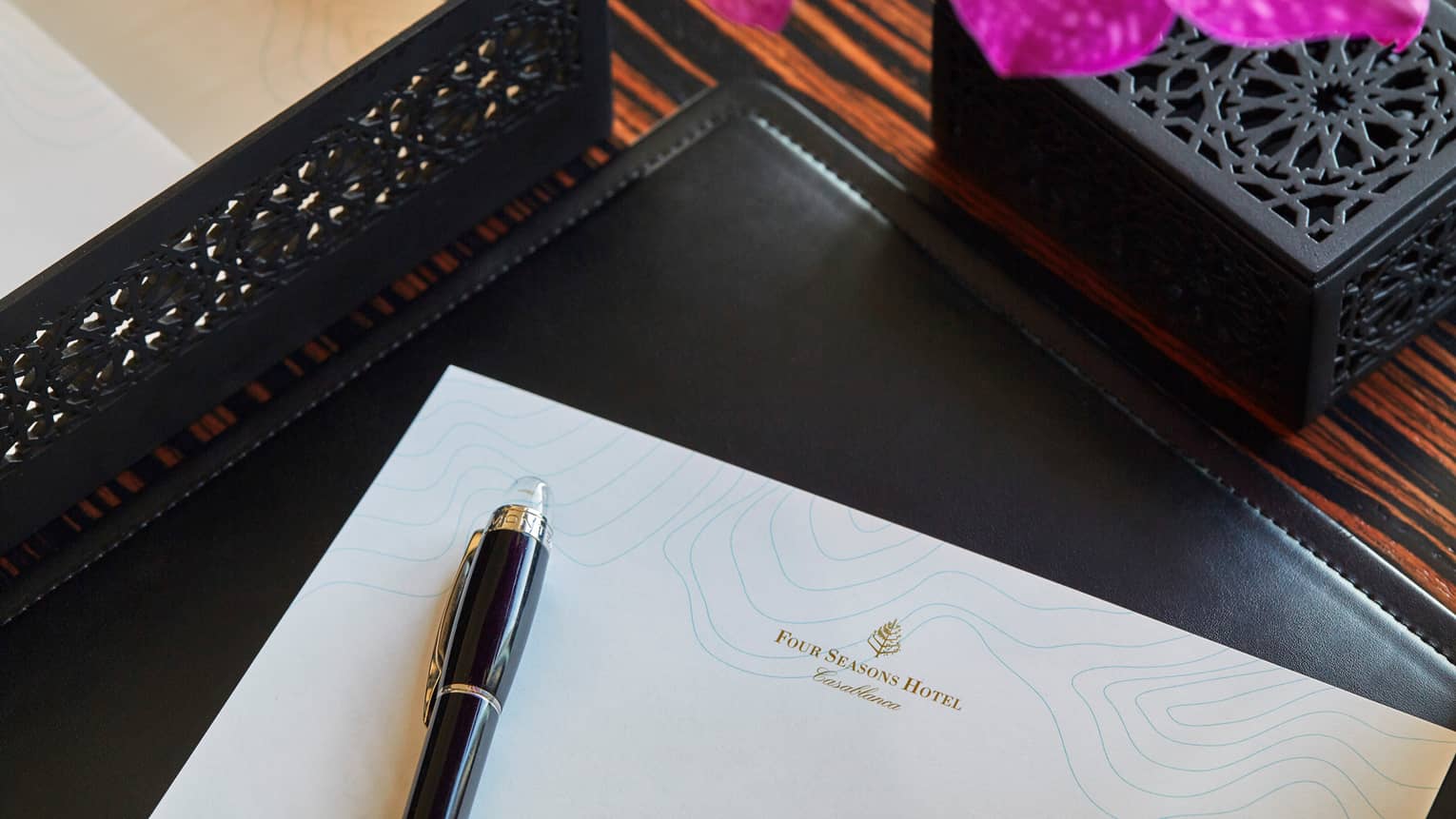 Corner of white piece of paper with Four Seasons logo, pen