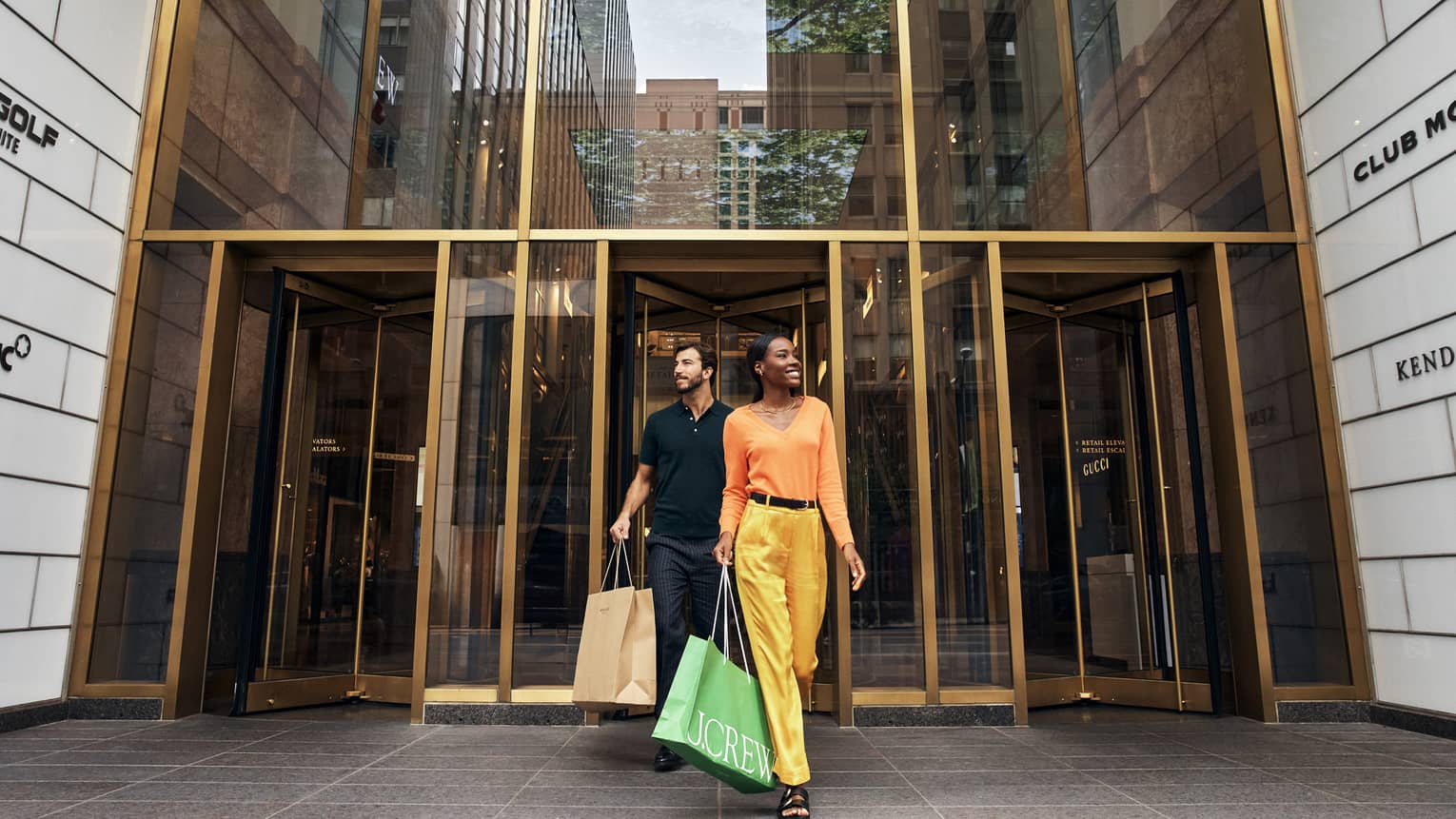 A man and woman walking out of a store with shopping bags.