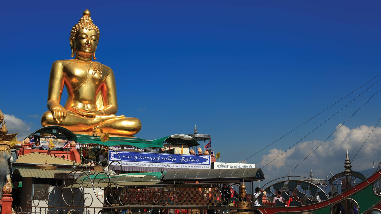 Gold Buddha statue on temple roof against a blue sky