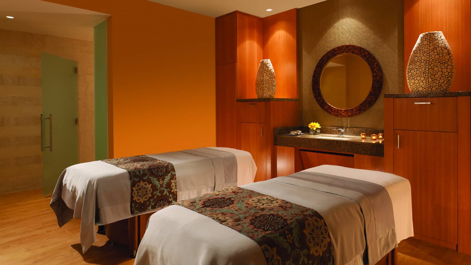 Candle-lit Couples Massage Suite beds with textiles side-by-side in spa