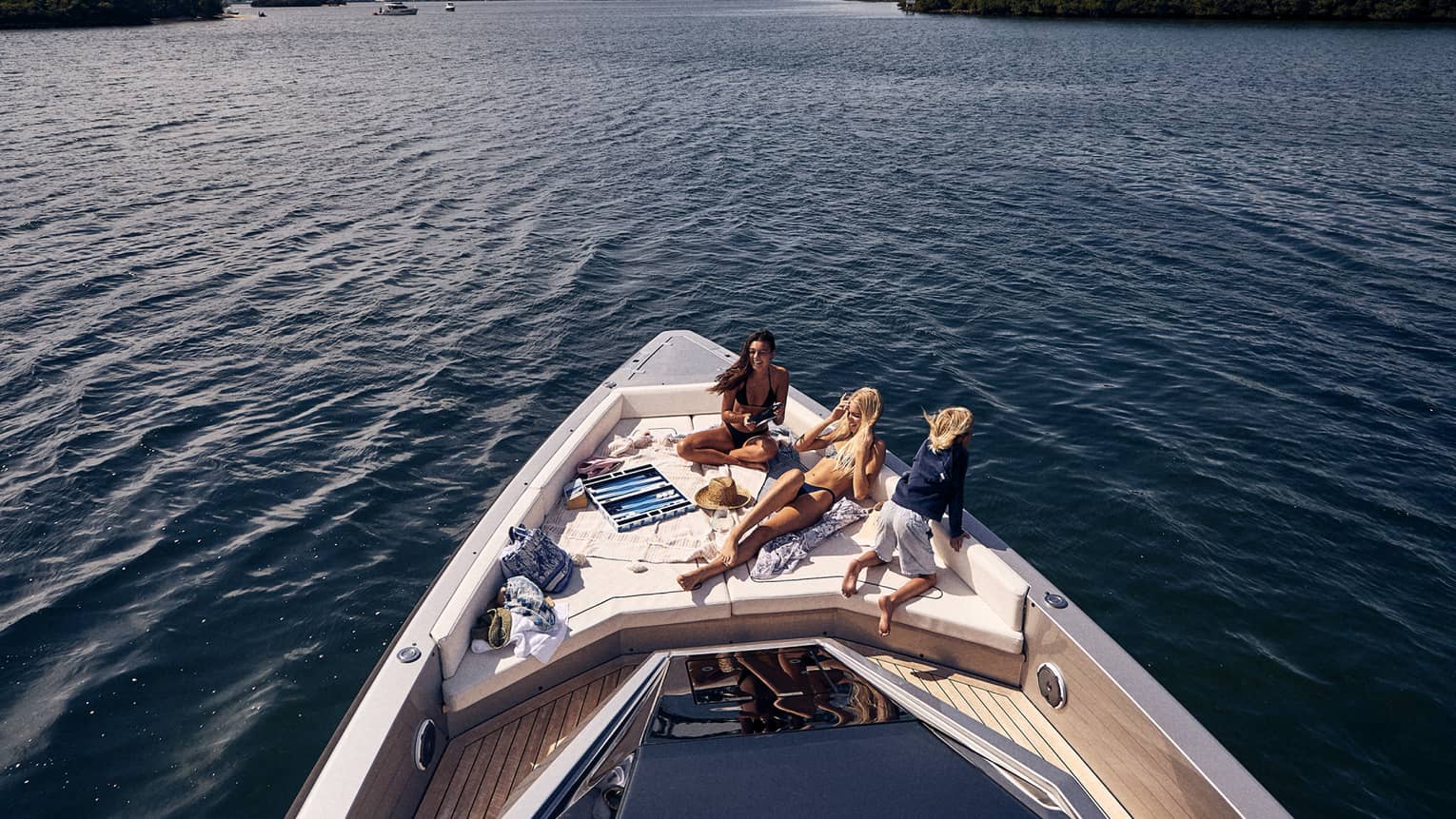 Three people lounging on the front of a boat deck.