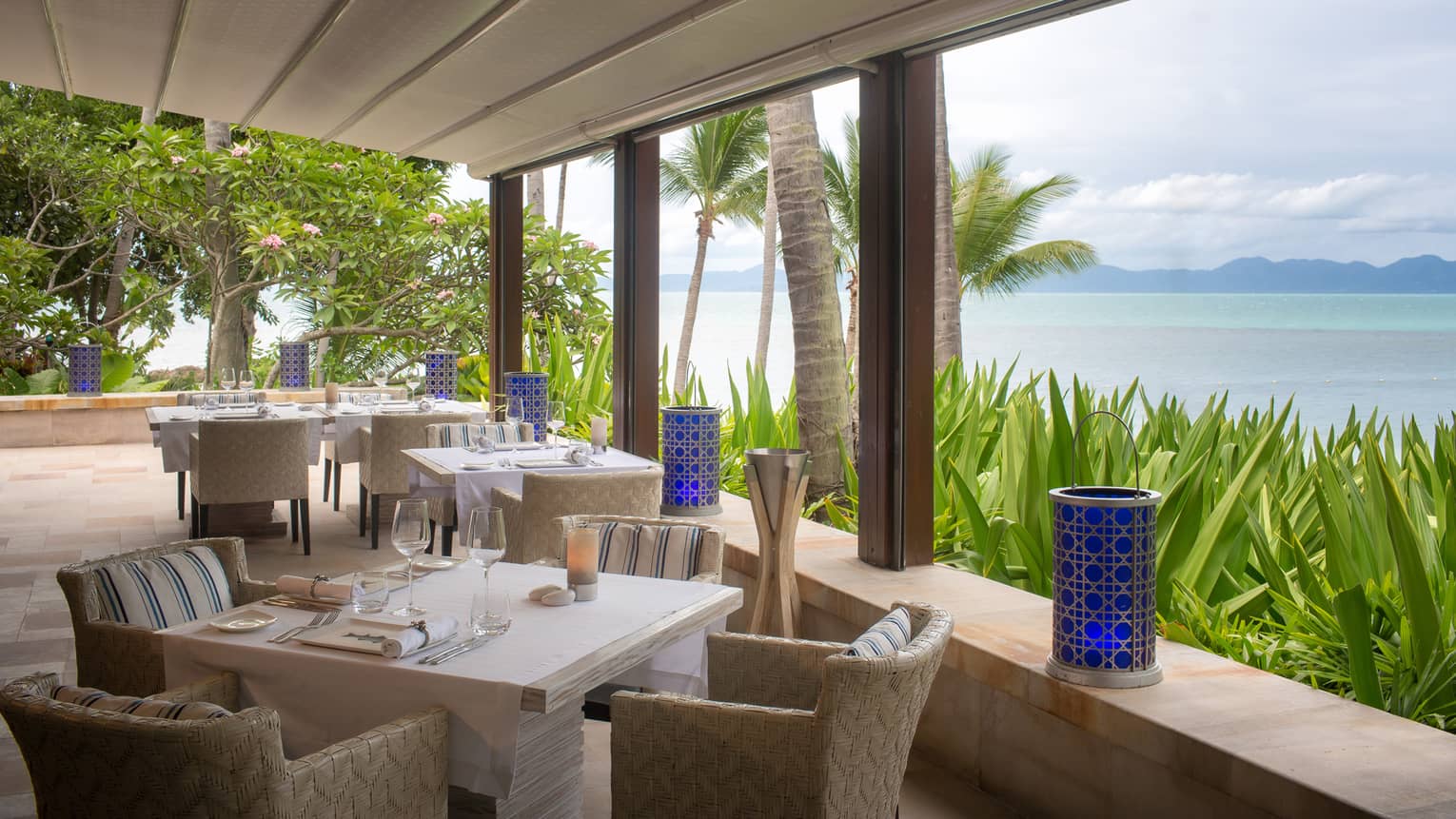 square tables overlooking the ocean are set for dinner
