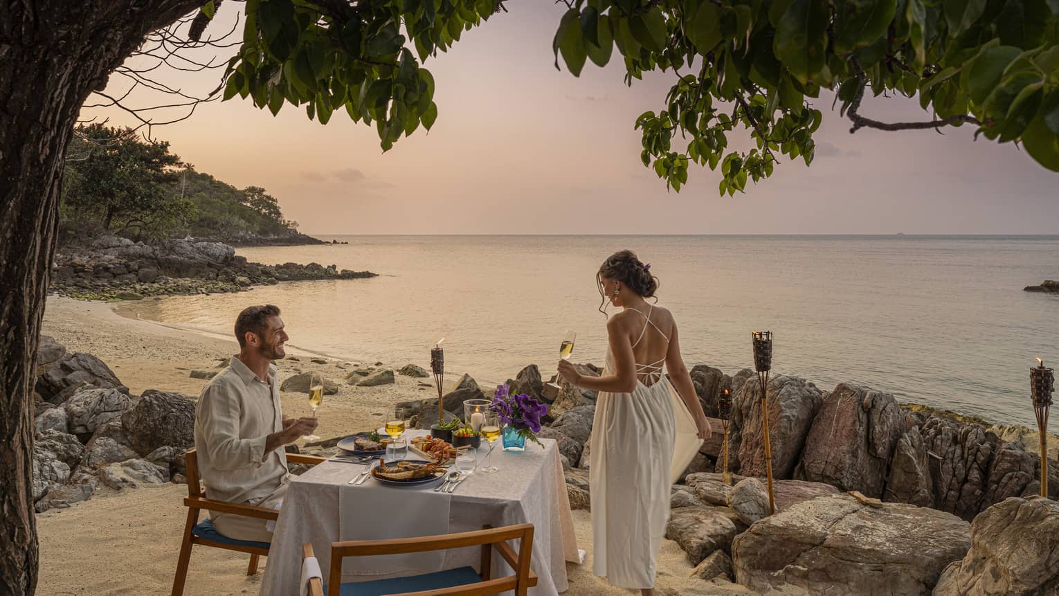 Couple enjoys romantic beachside dinner at sunset on the craggy shores