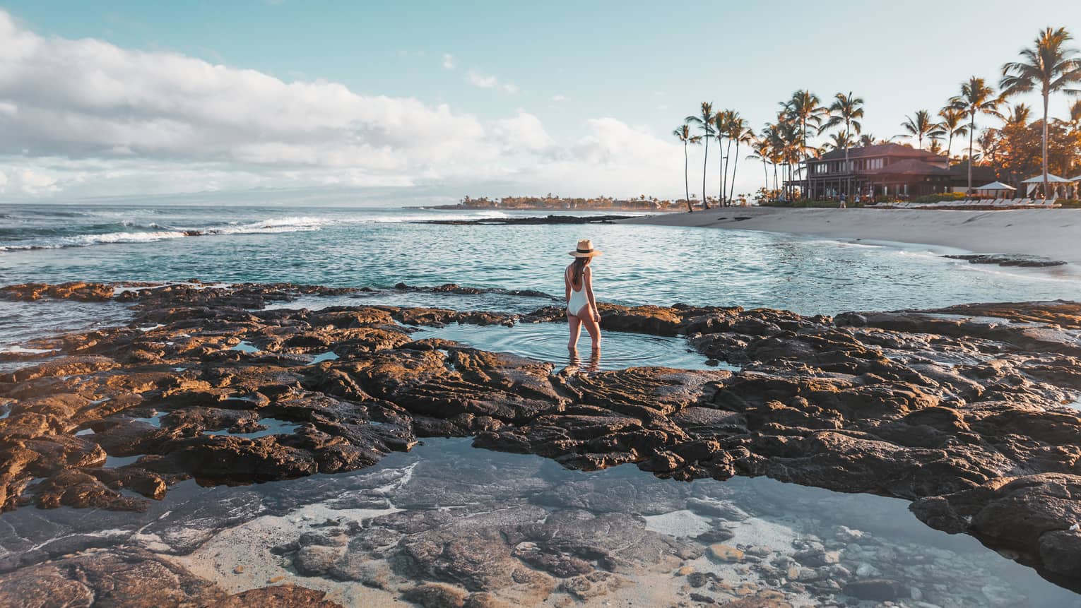 A guest exploring tidal pools by the beach in Hualalai