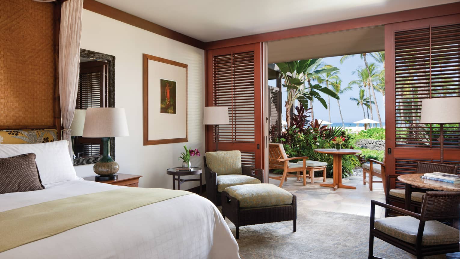 Ocean-View Room bed, wicker armchair and ottoman, wood shutters by open wall to patio 