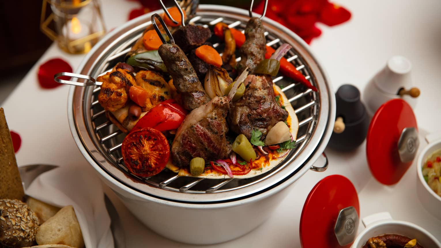 Several skewers of beef served on a small personal grill. 