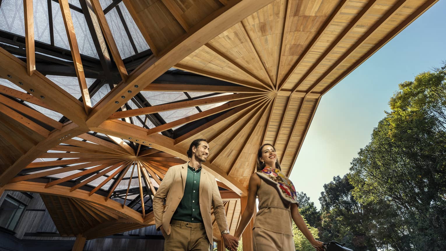 Couple walks hand-in-hand under the elaborate wooden awning of the Hotel