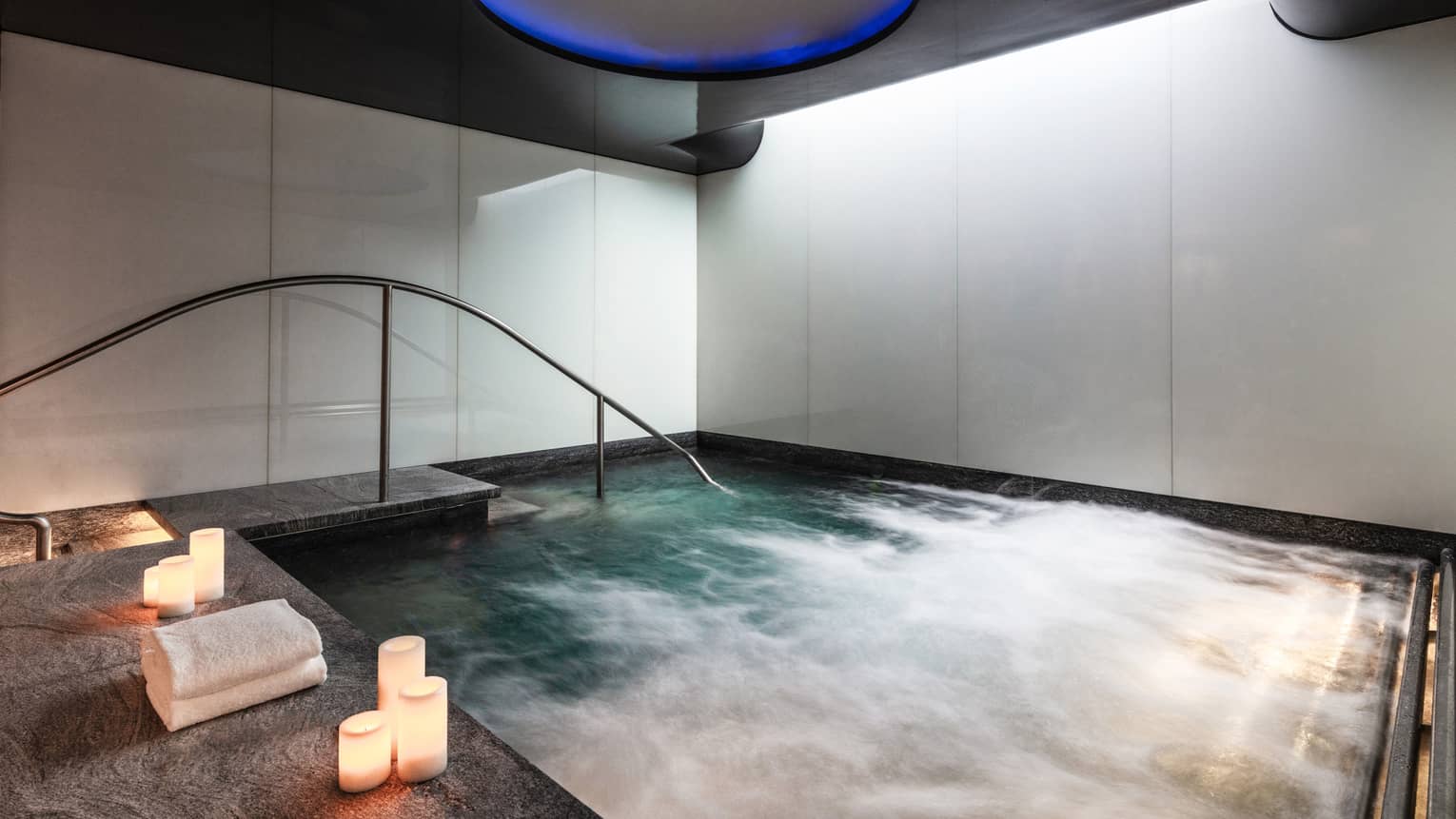 An indoor whirlpool with candle on the ledge.