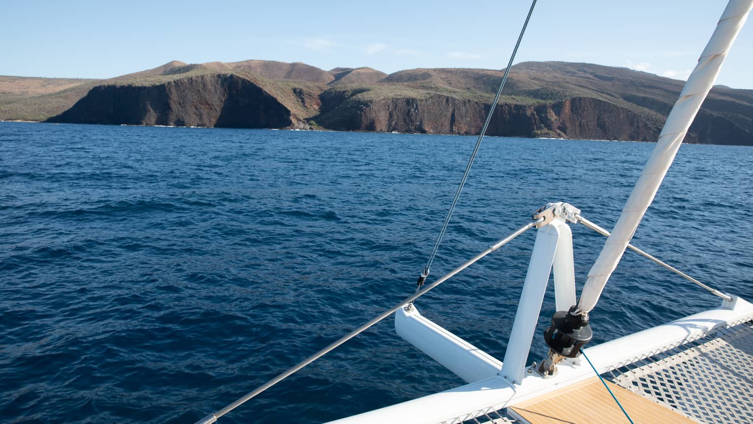 The edge of a boat looking out and land and water.